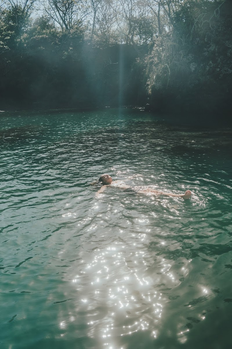 Floating in a sunlit turquoise jungle river pool