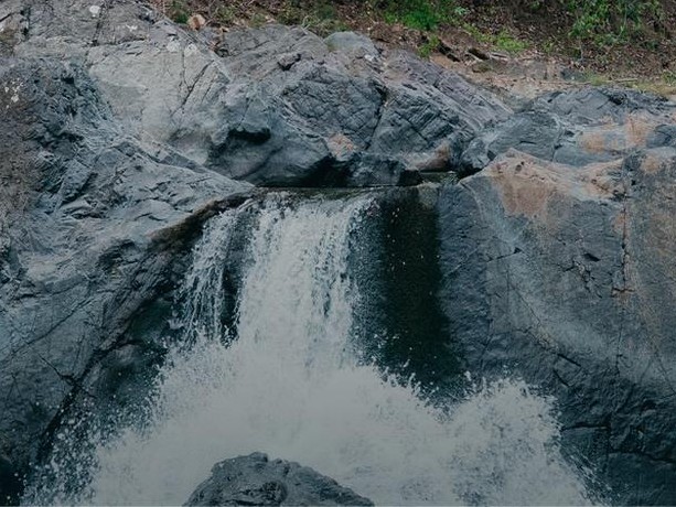 A jungle waterfall falling into a dark natural pool